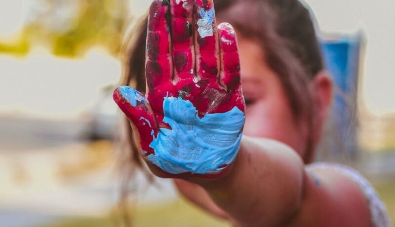 Mała dziewczynka pokazuje rękę pomalowaną w różne kolory