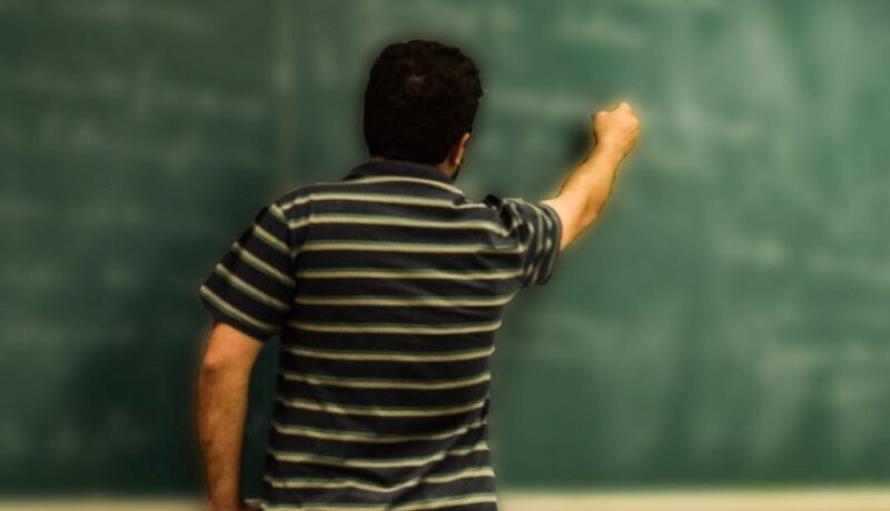 Nauczyciel pisze coś na tablicy